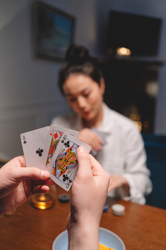 Focused close-up of a person holding cards during a poker game with a blurred background.